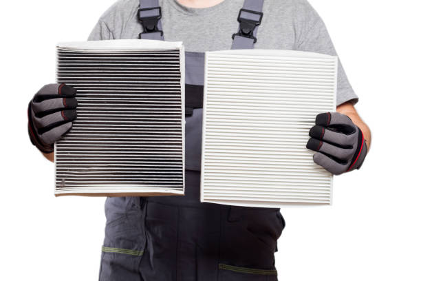 Car mechanic holding old dirty and new clean cabin filter, isolated on a white background Car mechanic holding old dirty and new clean cabin filter, isolated on a white background passenger cabin stock pictures, royalty-free photos & images