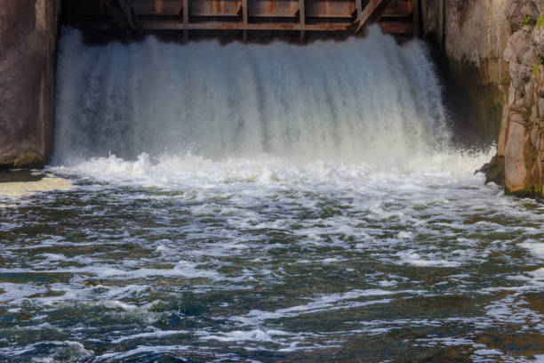 flowing water with water spray from the open sluice gates of a small dam - miniature weir imagens e fotografias de stock