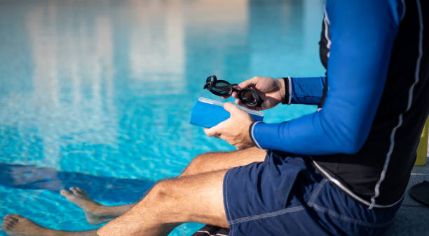 istock Man holding swimming goggles by the pool on a sunny day 1283476343