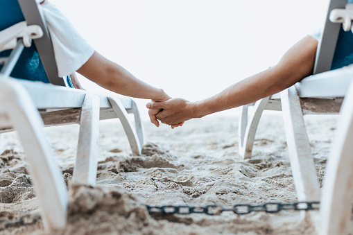 Couple sitting on the deck chairs at the beach. honeymoon, Love, travel or vacation concept.