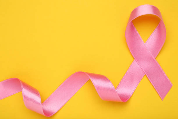 istock Cancer concept. Pink ribbon on yellow background 1283476724