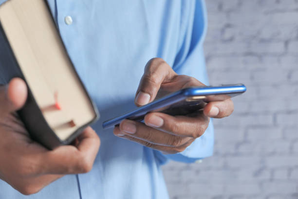 istock close up of man using smart phone and holding a book 1283477898
