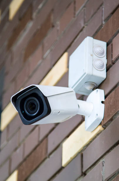 istock Closed-circuit television camera mounted on brick wall. CCTV security camera outdoors. 1283478352