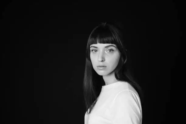 Photo of Studio portrait of a young woman against plain black background