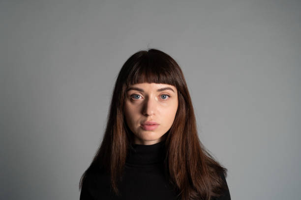 Studio portrait of a young woman against plain grey background