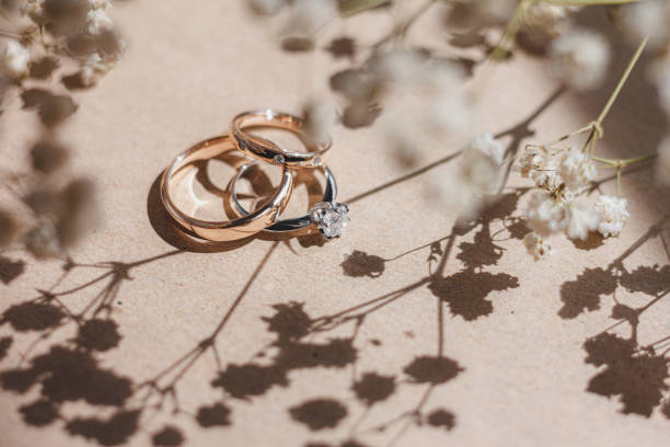 Diamond engagement ring and wedding rings Gorgeous white gold engagement ring with a big diamond and two beautiful rose gold wedding rings placed between flowers and shadows. diamond ring photos stock pictures, royalty-free photos & images