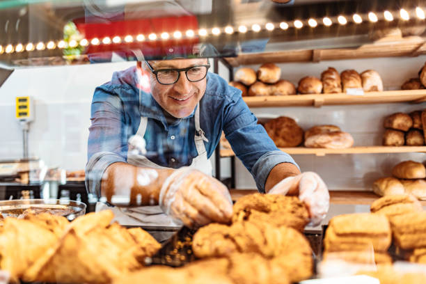 istock Man working at a bakery and serving fresh bakery from the display cabinet 1283481785