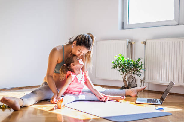 schwangere mutter praktiziert yoga mit tochter zu hause - relaxation exercise child mother human pregnancy stock-fotos und bilder