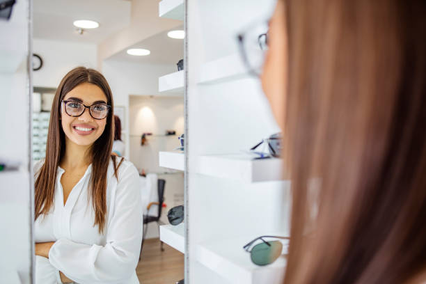 istock Woman looking with glasses in mirror at optician store 1283484313
