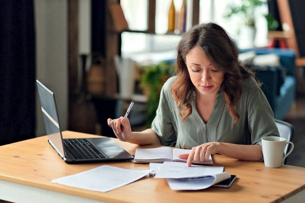 istock Young woman working from home office. Freelancer using laptop and the Internet. Workplace in living room 1283484443