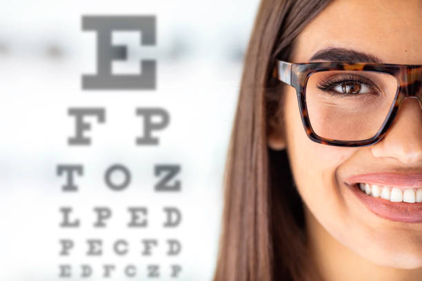 primer plano de una joven que lleva gafas con un diagrama ocular en el fondo. - sensory perception eyeball human eye eyesight fotografías e imágenes de stock