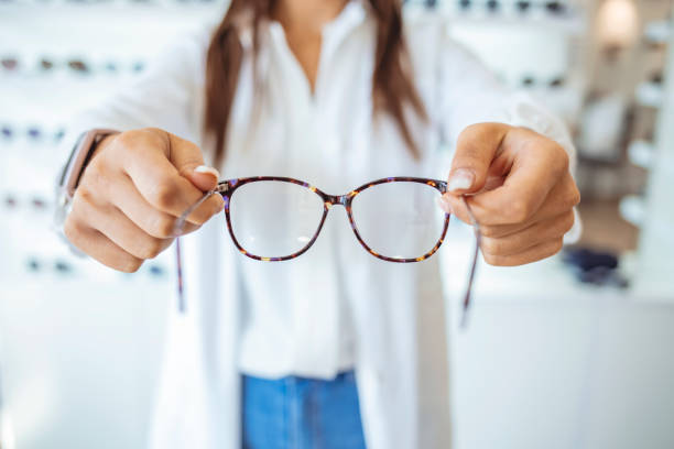 opticien affichant et suggérant des lunettes dans le magasin optique - eyewear eyesight new personal accessory photos et images de collection