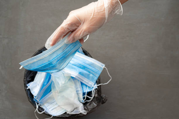 istock Hand putting used dirty surgical mask to  a garbage bin. 1283485981