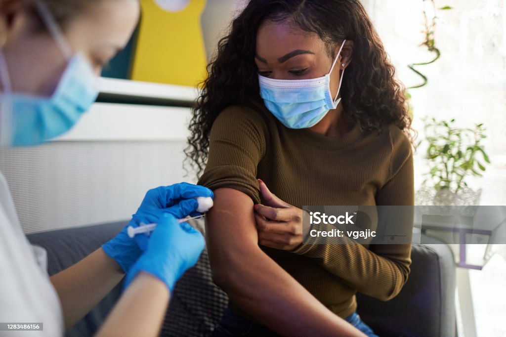 Vaccination At Home. African family get vaccinated at home during pandemic times. Vaccination Stock Photo
