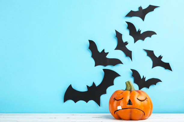 istock Halloween paper bats with orange pumpkin on blue background 1283486990