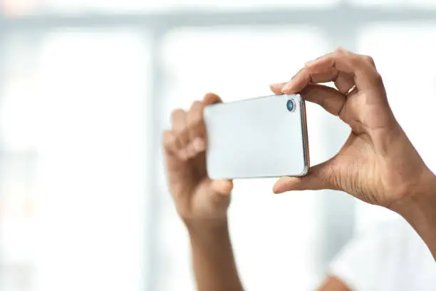 Cropped shot of an unrecognisable woman photographing the interior of a house with a smartphone