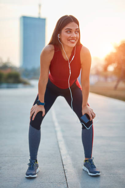 istock Modern young woman with cellphone making pause during jogging / exercise. 1283487222