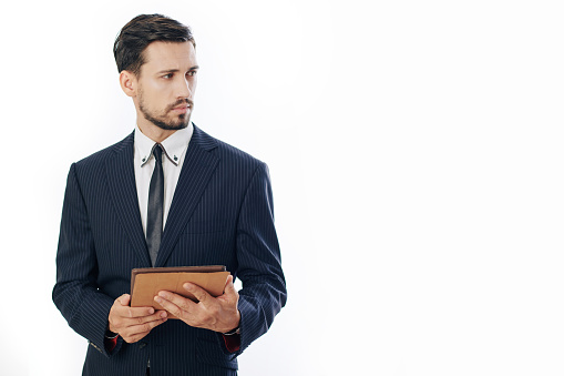 Portrait of serious young entrepreneur with tablet computer looking away, isolated on white