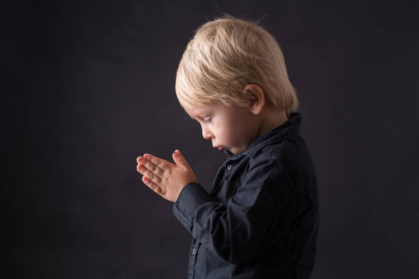 istock Little toddler child, boy praying, isolated background 1283491059