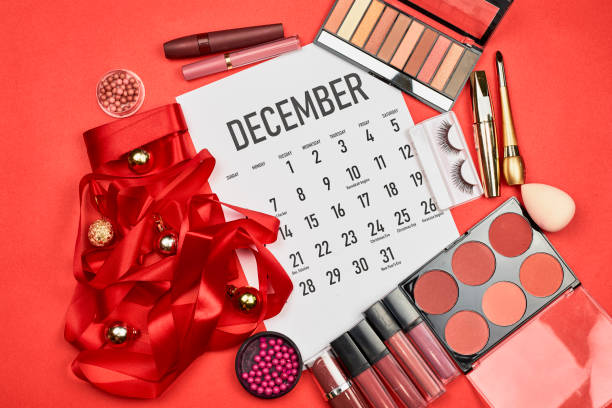 December monthly calendar and Christmas tree made with bright ribbon, festive baubles, and professional make-up set with different cosmetics products