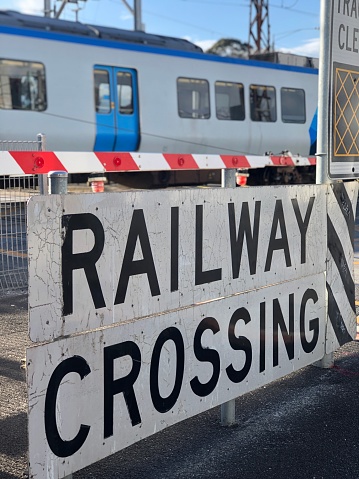 Close of a railway crossing sign with a train in the background