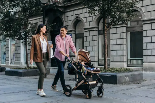 Happy family with baby in a stroller walking down the street and shopping