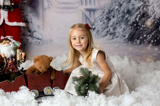 Sweet little girl with christmas decorations, playing in the snow