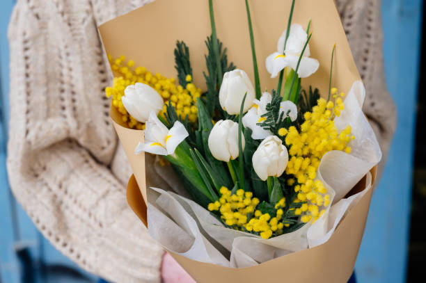 букет цветов в бежевом пакете в руках. - tulip blue close up cut flowers стоковые фото и изображения