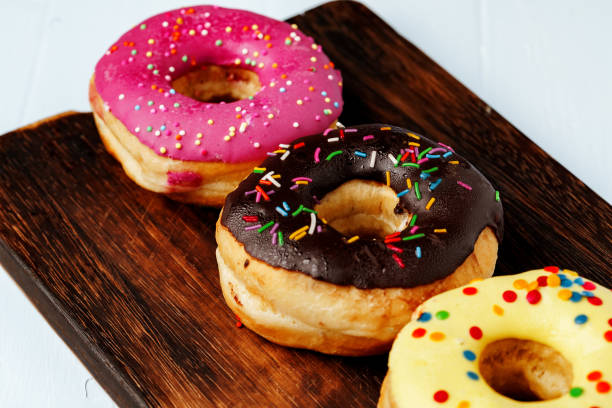 istock Glazed donuts with sprinkles on wooden board 1283494879