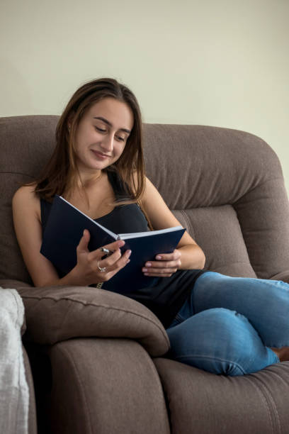 istock woman sitting in comfy sofa reading diary book enjoy free time 1283496542