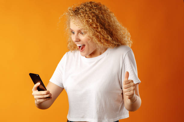 istock Young blonde curly girl using her smartphone 1283496572