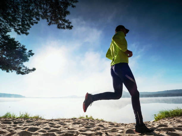 istock Sports man on the beach runs side by the sun, 1283497670