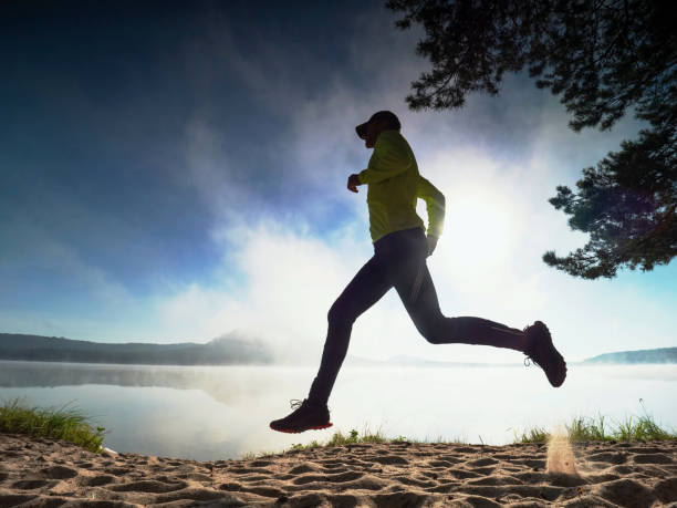istock Tall slim runner on sandy bay along lake. Healthy  style 1283497963
