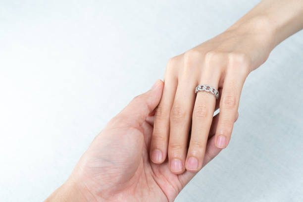 istock Man putting diamond ring on woman hand over white background. 1283498325