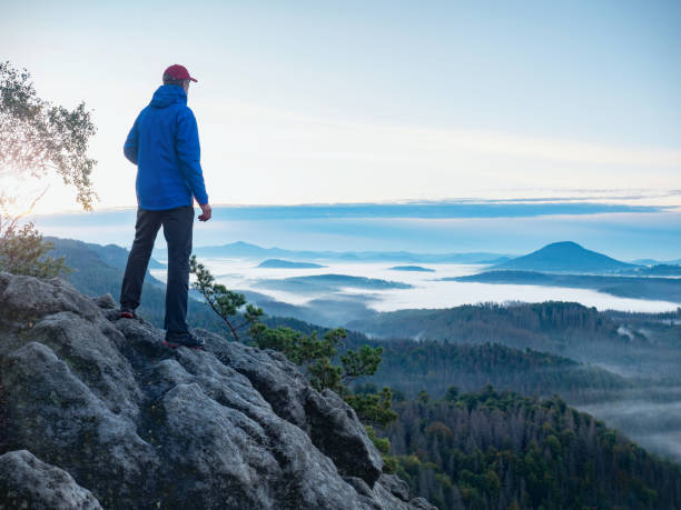 istock Man on the mountain peak looking on mountain valley 1283498330