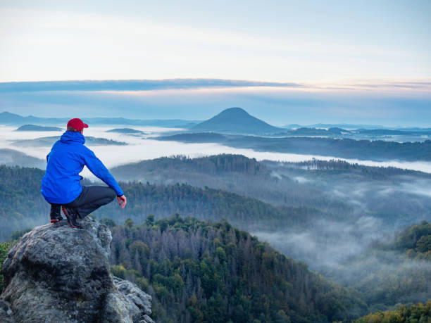 istock Man on sharp rocky edge, enjoy amazing birds view 1283498383