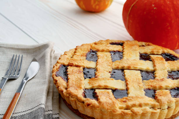 istock Berry tart pie and orange pumpkin on wooden table 1283498409