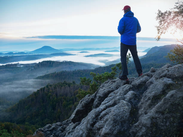 istock Man watch thick mist in valley from rocky view point 1283498649
