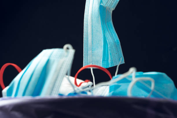 istock Hand putting used dirty surgical mask to  a garbage bin. 1283498665