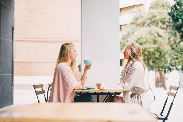istock Two beautiful blond girls talking while sitting in a cafeteria having breakfast. 1283499333