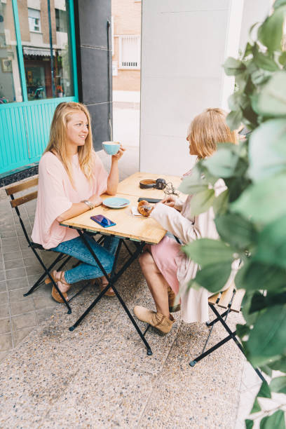 istock Blonde girl drinking coffee in a blue cup while talking to her friend 1283499348