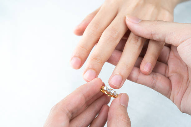 istock Man putting diamond ring on woman hand over white background. 1283499547