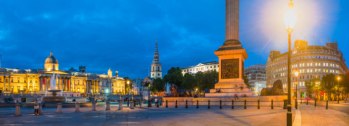 The iconic tower of Nelson’s Column overlooking the fountains of Trafalgar Square and St. Martin’s in the Fields at dusk in the heart of London, UK.