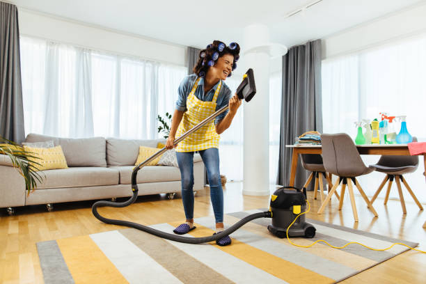 istock Woman enjoying singing using vacuum cleaner tube as mike 1283502158