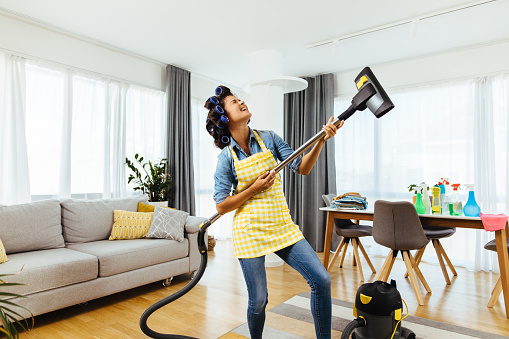 Woman holding a vacuum cleaner like a guitar and singing