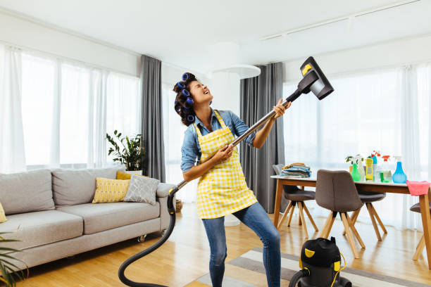 woman holding a vacuum cleaner like a guitar and singing - spring cleaning women cleaning dancing imagens e fotografias de stock