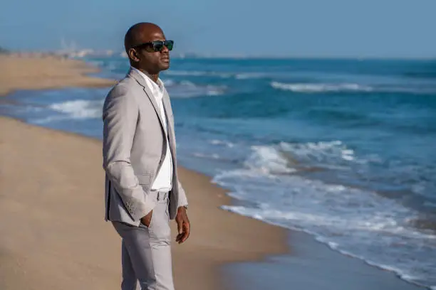 African american tourist suit businessman relax on the beach with sunglasses