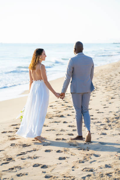 istock Multi ethnic couple elegant walking on the beach barefoot 1283504804