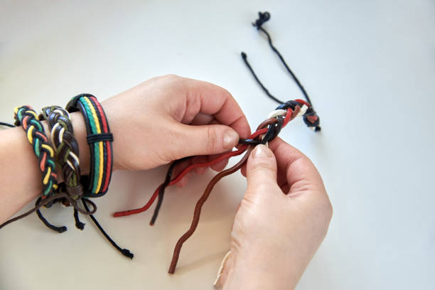 istock Woman's hands making a leather bracelet on a white background. 1283505006