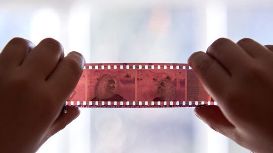 A woman holds a negative from an old film camera, close-up.